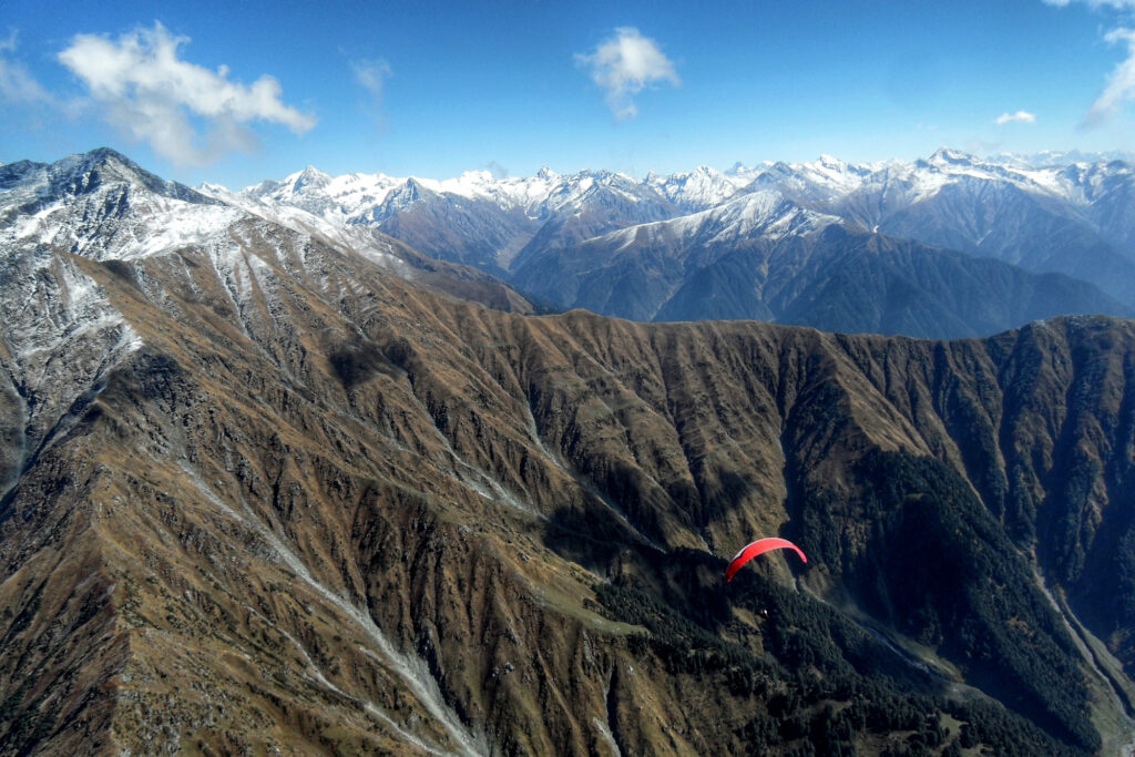 インドの雄大な山岳地帯でパラグライダー海外フライトを行っている風景